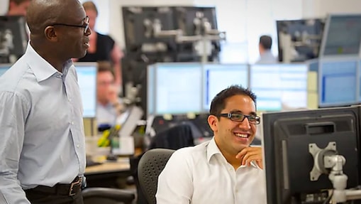 Two traders at Shell working together and smiling.