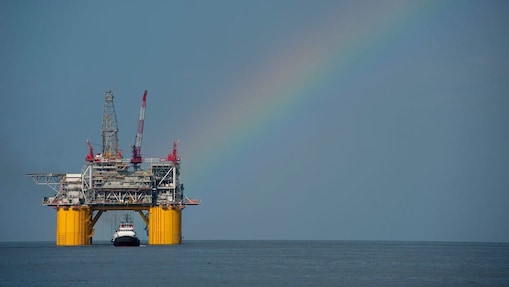 A Shell offshore rig with a rainbow in the background.