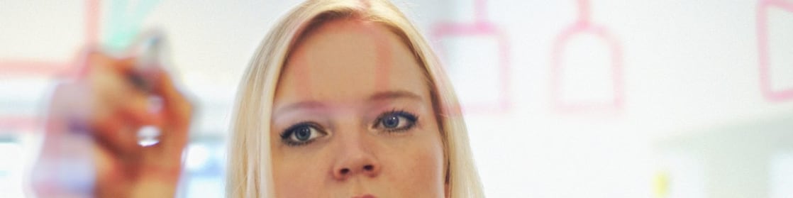 Sweden, Businesswoman writing on glass wall in office