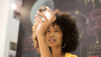 Businesswoman examining crystal ball in office