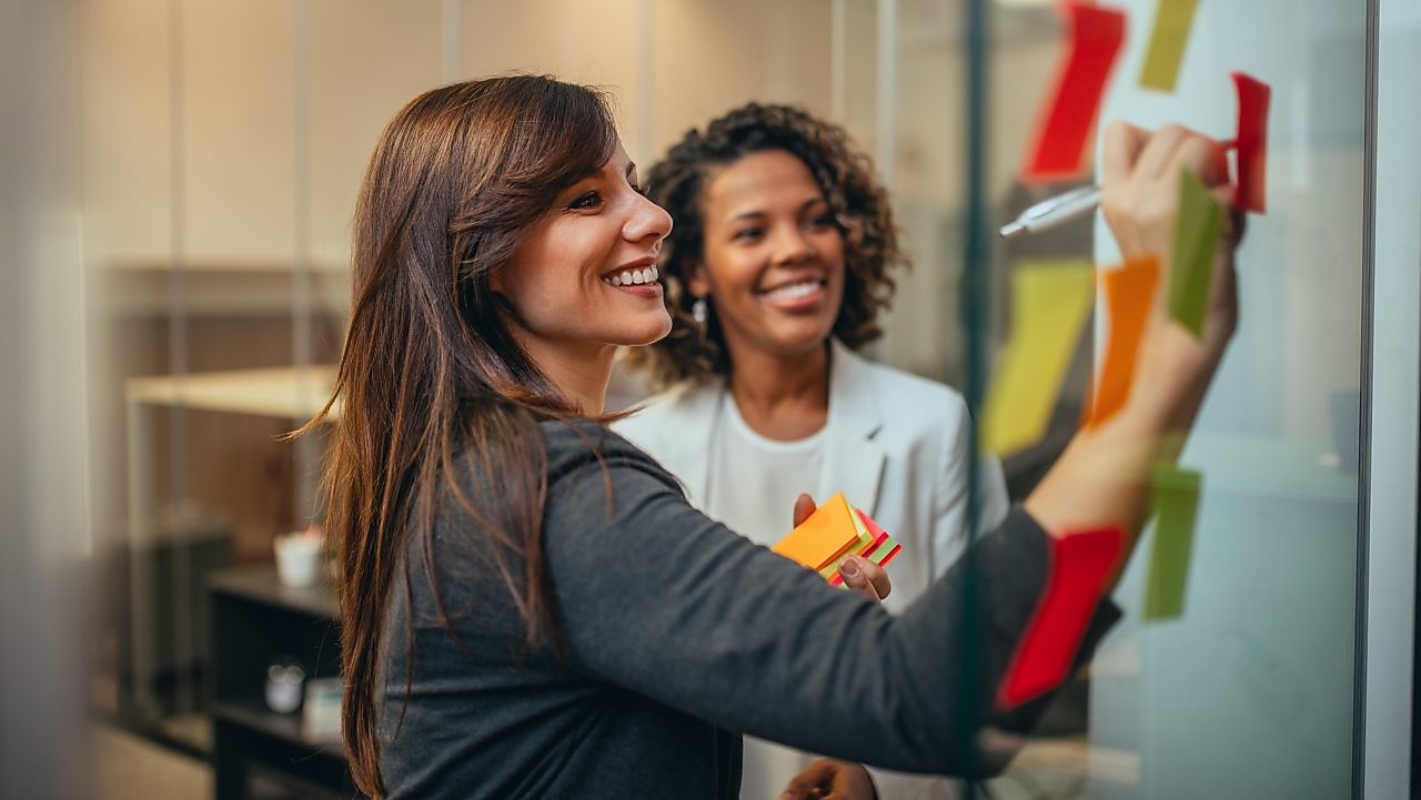 Woman writing on board and smiling