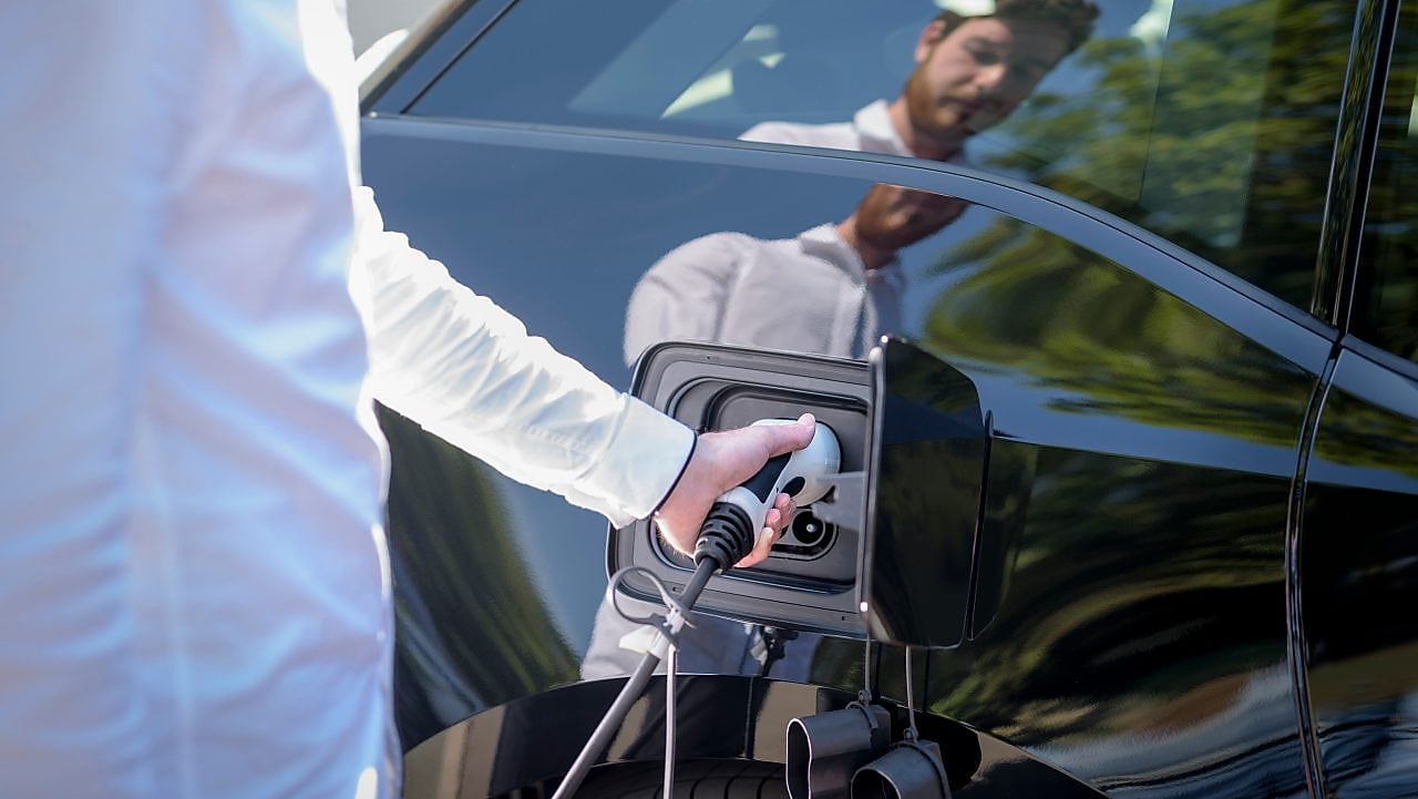 Man’s reflection in the window while charging an EV