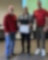 group of people standing in front of screen. Woman is holding a certificate.