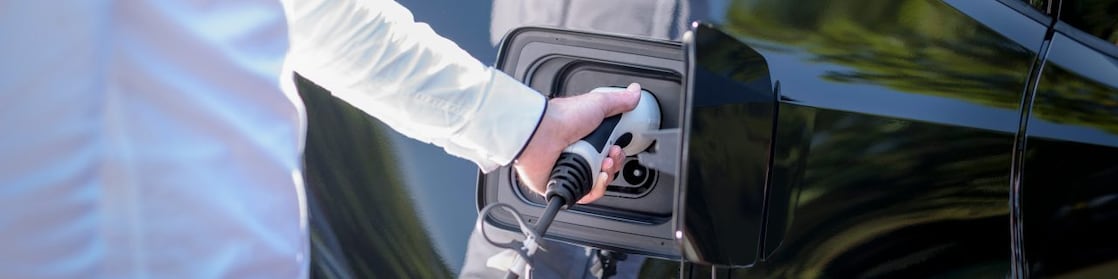 Man’s reflection in the window while charging an EV