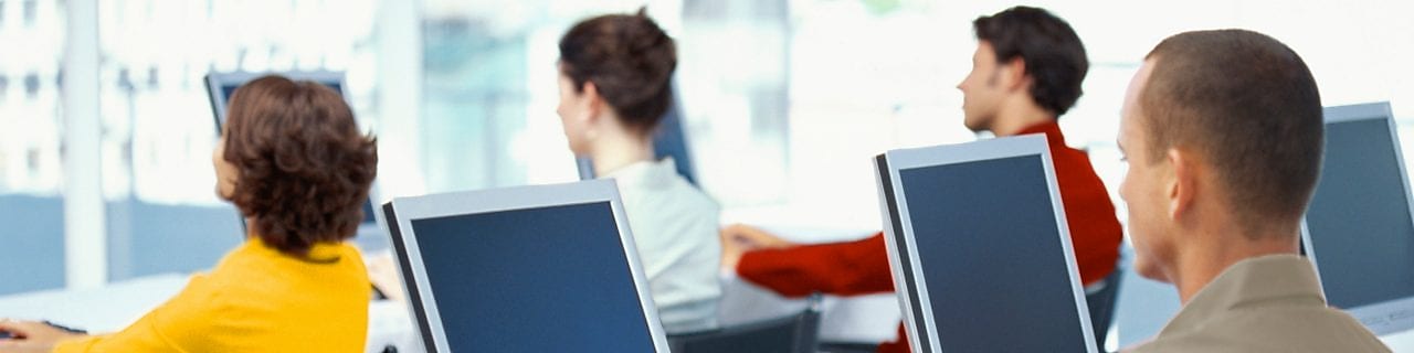 rear view of four business executives using computers in an office