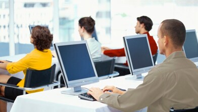 rear view of four business executives using computers in an office