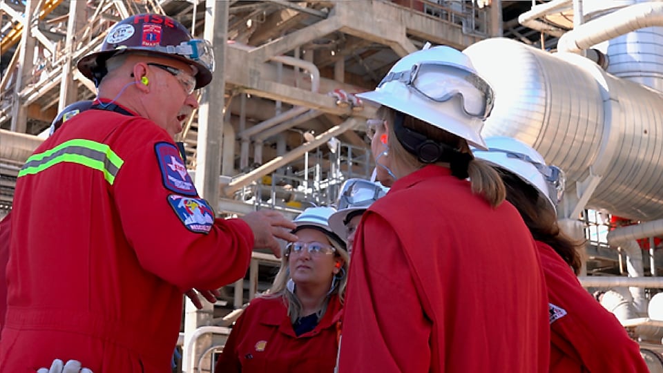 A Shell employee discusses operations with WBENC members near an operational unit