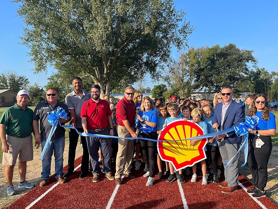 A large group of donors, students and faculty pose for a ribbon cutting ceremony to celebrate the schools' new field track.