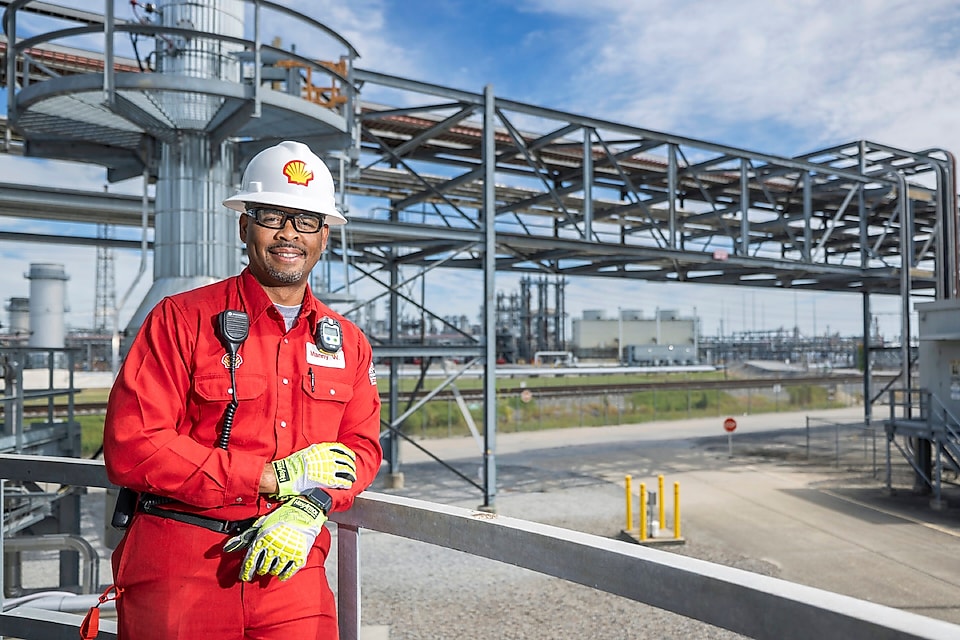 Geismar employee smiles in front of industrial facility.