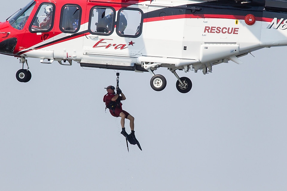 A man being pulled up to a helicopter