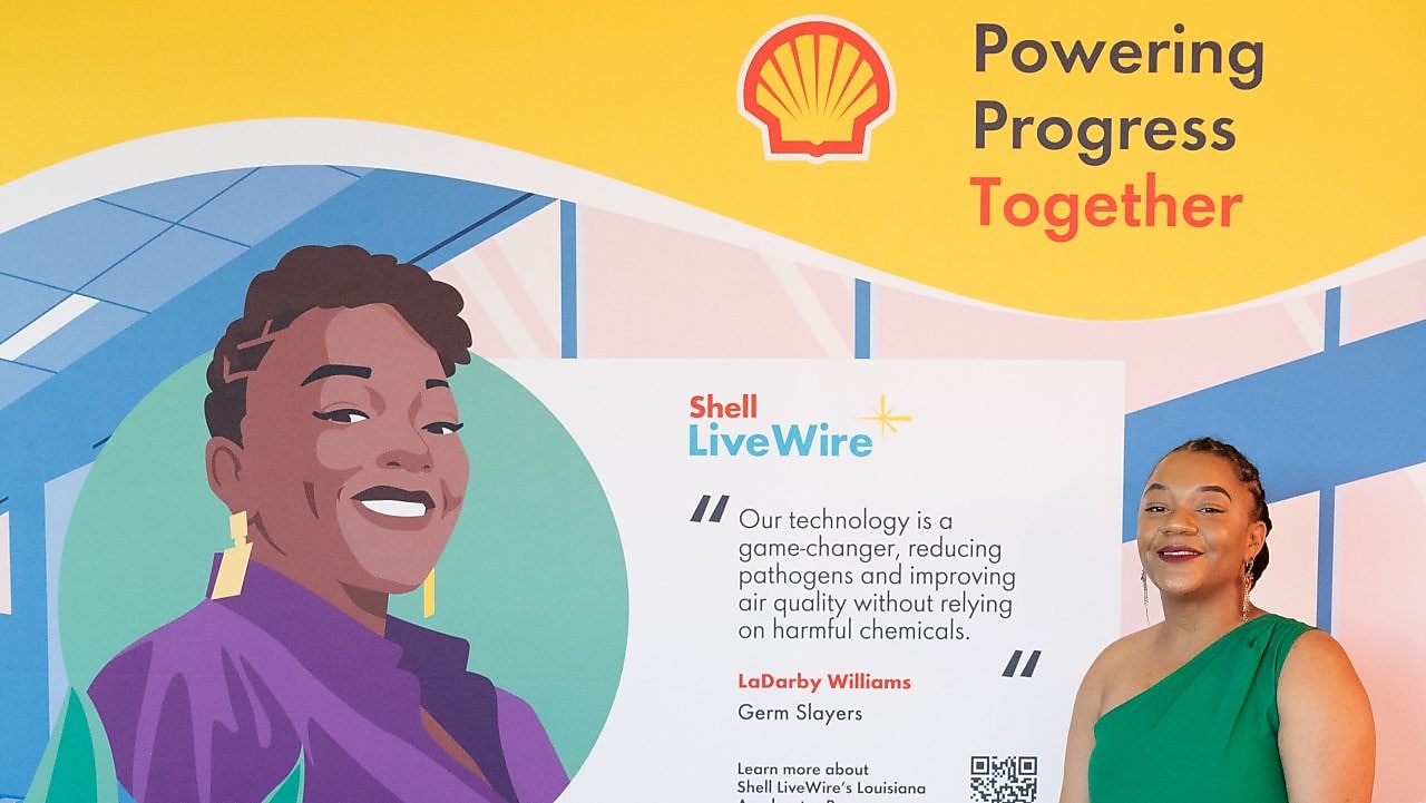 Young women posing next to a custom-made banner