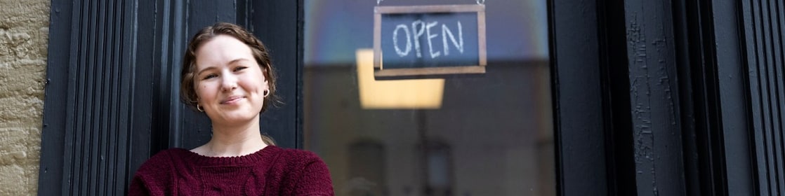 Young women standing outside of business with an open sign