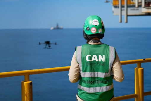 Woman’s back with drone flying above ocean