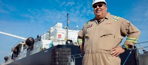 Man in coveralls standing in front of a barge