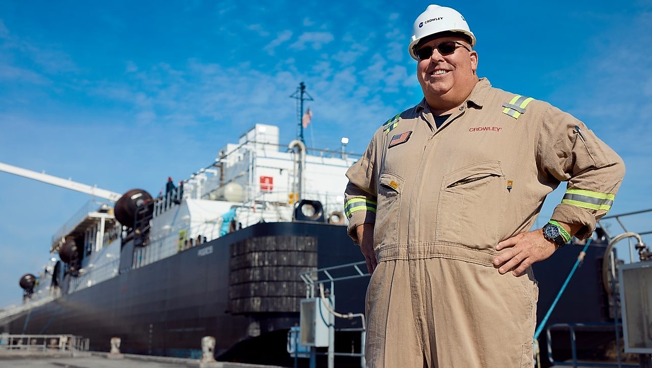 Man in coveralls standing in front of a barge