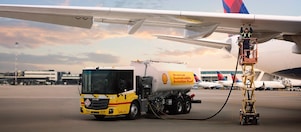 A man fueling a commercial airplane from a fuel truck at an airport