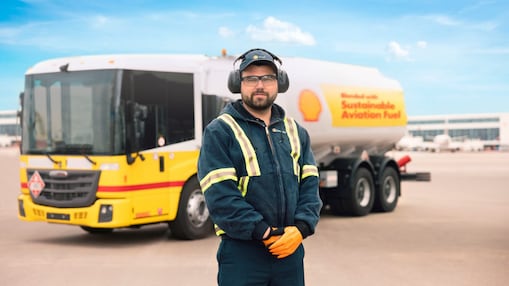 A person wearing a safety suit and headphones standing in front of a truck