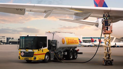 A man fueling a commercial airplane from a fuel truck at an airport