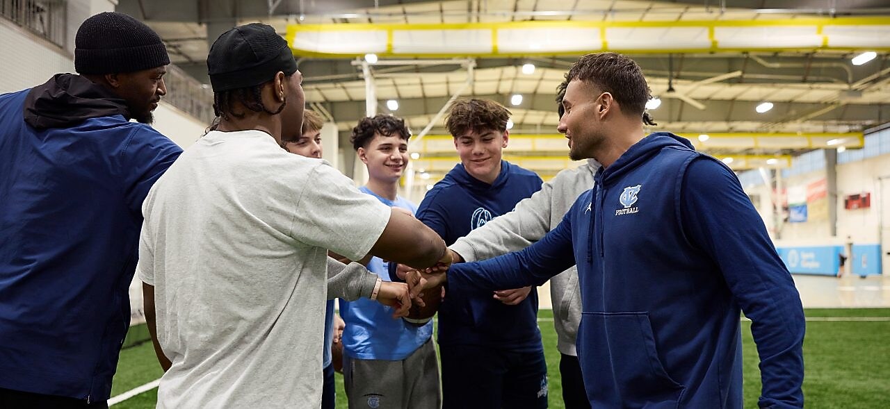 Young men in a sports huddle on an indoor field