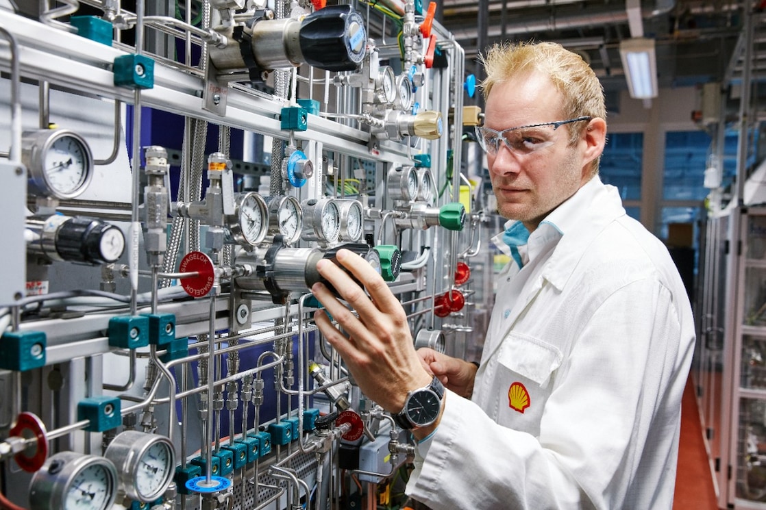 A guy wearing glasses and a white coat with Shell's logo playing with an electronic board