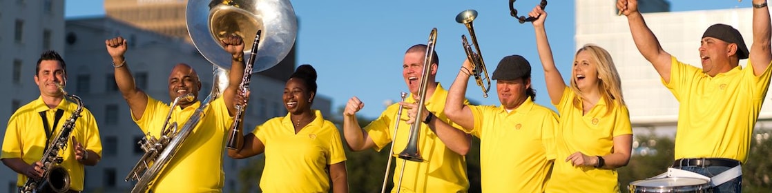 Shell Louisiana musicians in yellow shirts, holding their instruments celebrate making music.