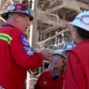 A Shell employee discusses operations with WBENC members near an operational unit
