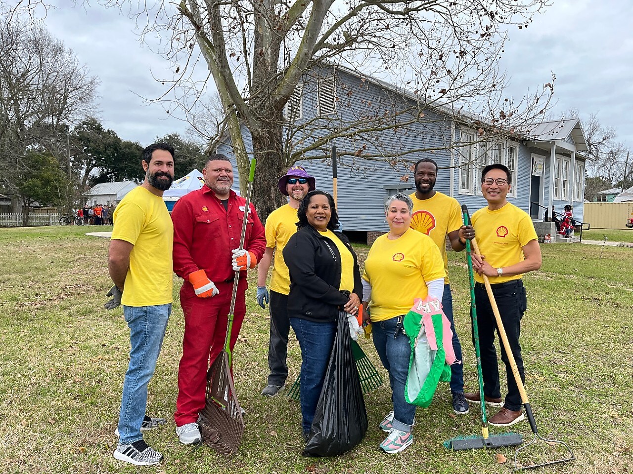 A group of volunteers smile with yard tools as they participate in local clean-up event.