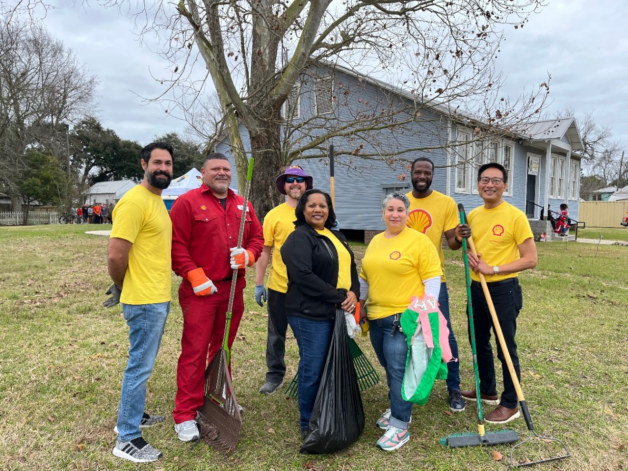 A group of volunteers smile with yard tools as they participate in local clean-up event.