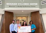 Four people smile while presenting a check of $15,000 to Teach for America.