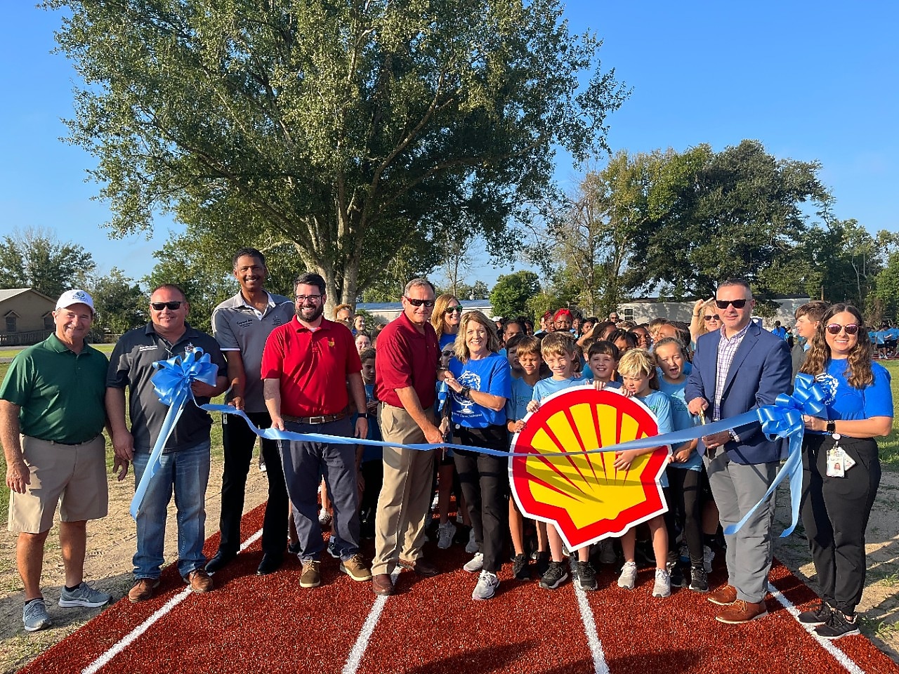 A large group of donors, students and faculty pose for a ribbon cutting ceremony to celebrate the schools' new field track.