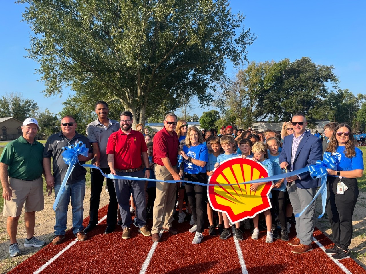 A large group of donors, students and faculty pose for a ribbon cutting ceremony to celebrate the schools' new field track.
