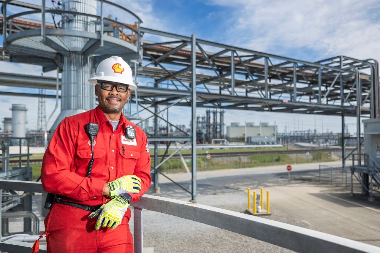 Geismar employee smiles in front of industrial facility.