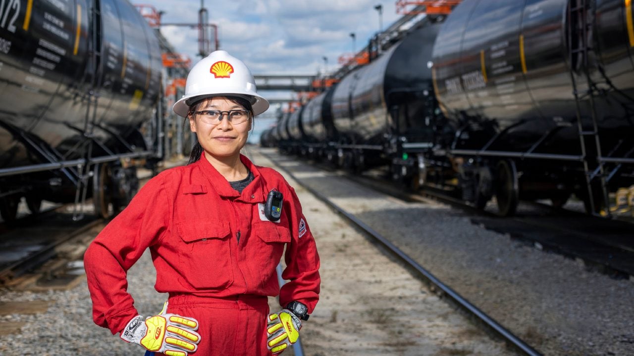 Woman poses in front of rail yard.
