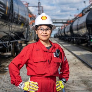 Woman poses in front of rail yard.