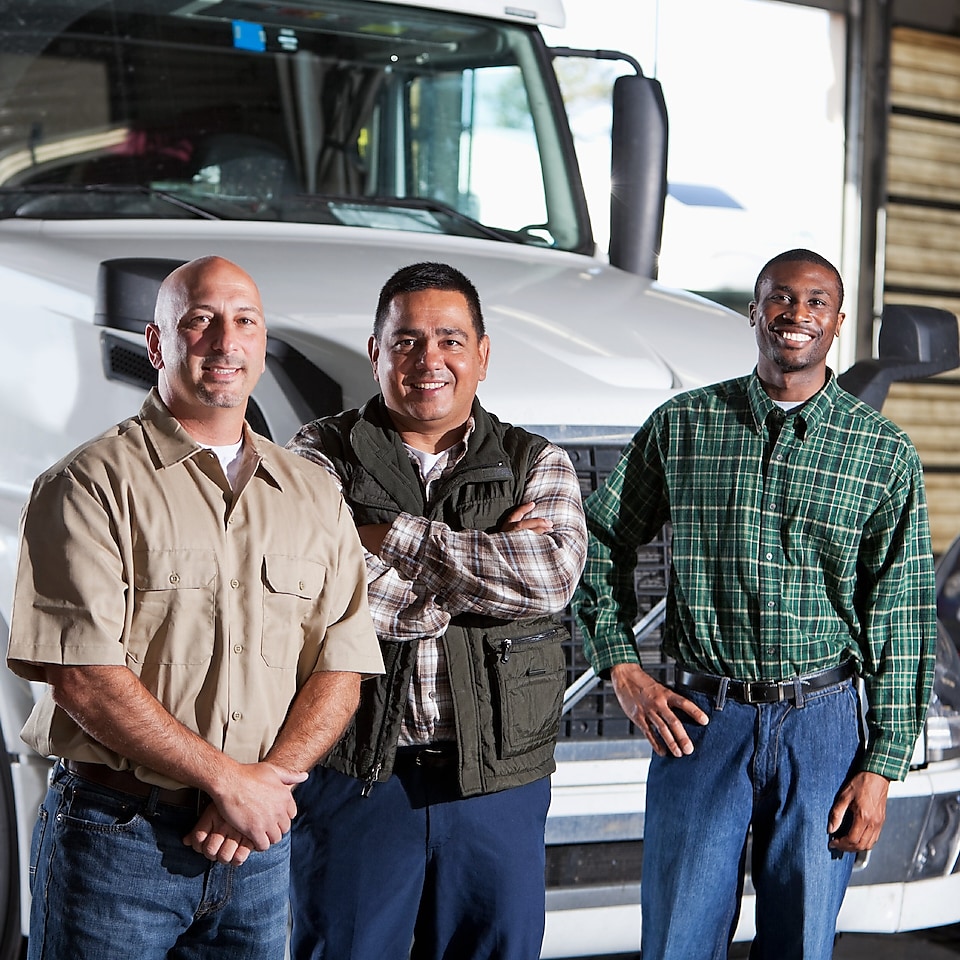 Three men standing in front of white truck cab