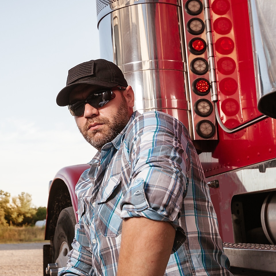 Man with sunglasses standing beside red truck cab