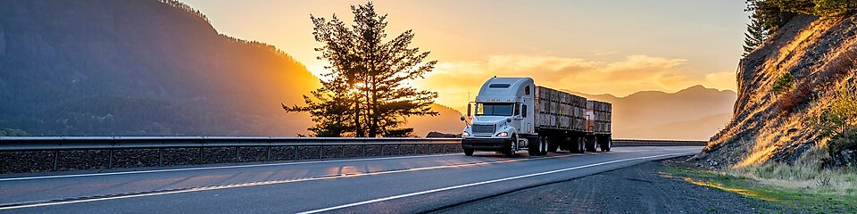 Truck driving on road at sunset