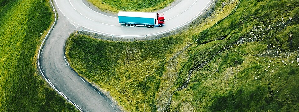 Truck driving through forest lined road