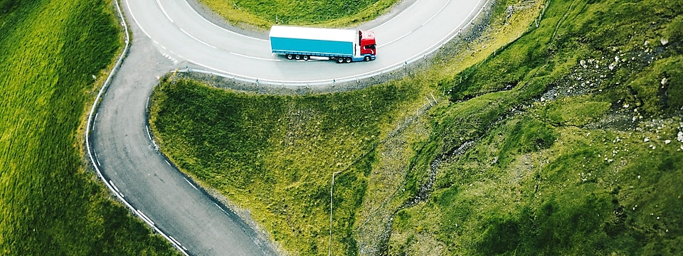 Truck driving through forest lined road