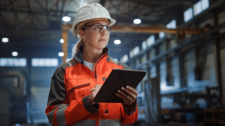 woman in a steel mill in PPE with a clipboard