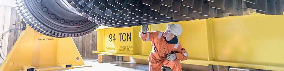 A power engineer inspects the blades of an industrial wind turbine.