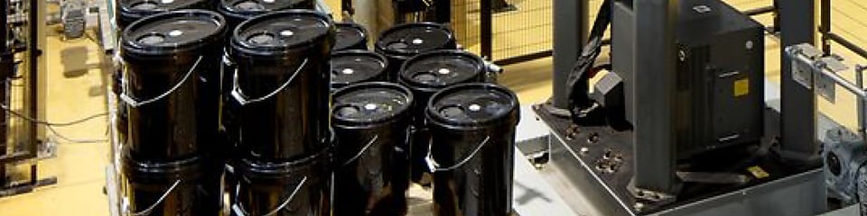Black 5-gallon buckets in an industrial setting 