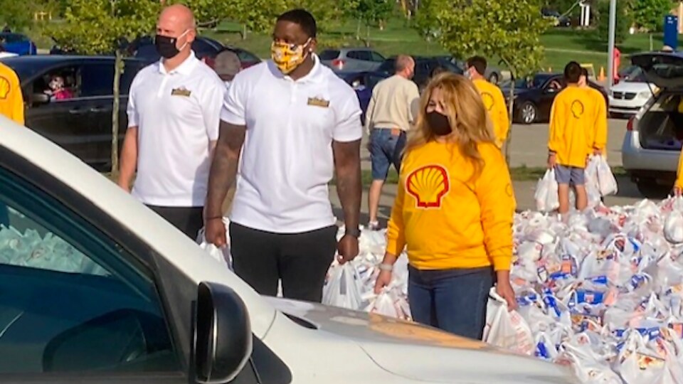Chris Hoke (left), Arthur Moats (right) and a Shell Polymers volunteer wait with bags of food and supplies. Photo courtesy of Patti Conley and the BCT staff.²