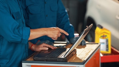 Two technicians using Shell resources and recommendations to select the right oil for each vehicle.