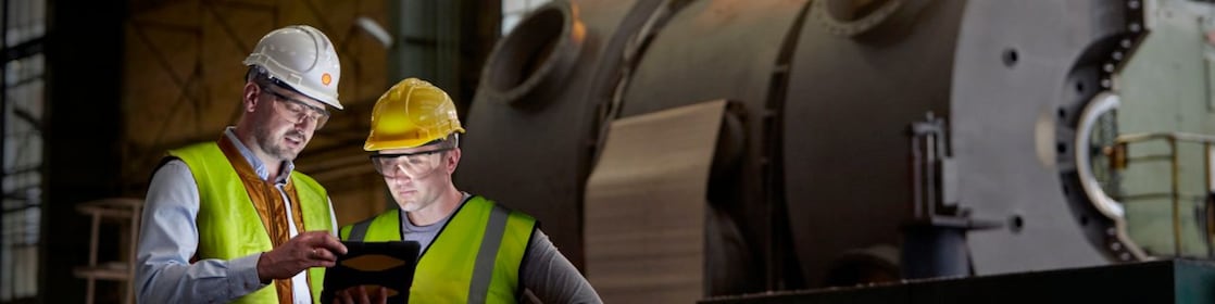 Male engineer and worker using digital tablet in dark factory