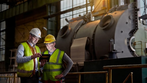Male engineer and worker using digital tablet in dark factory