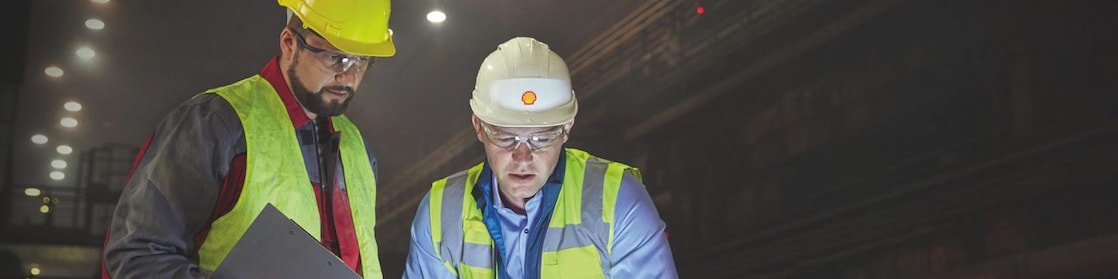 Steelworkers using laptop in dark steel mill