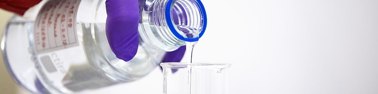 Technician pouring clear fluid into a flask