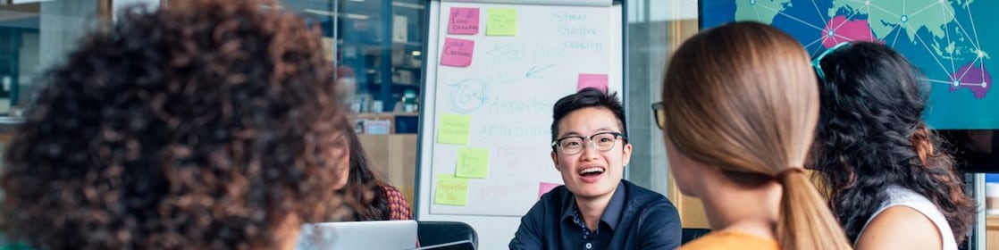  Four business people sitting around a round table reading documents, grey and yellow carpet