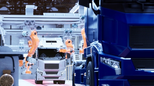 truck on a conveyor belt in a factory being assembled by robot arms